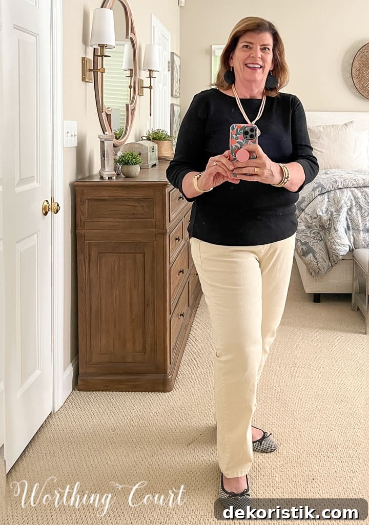 woman wearing black top with ivory pants taking selfie