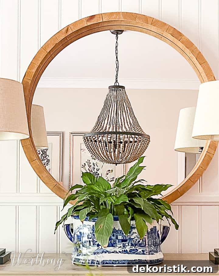 Dining room sideboard with round mirror, buffet lamps and blue and white urn filled with a plant
