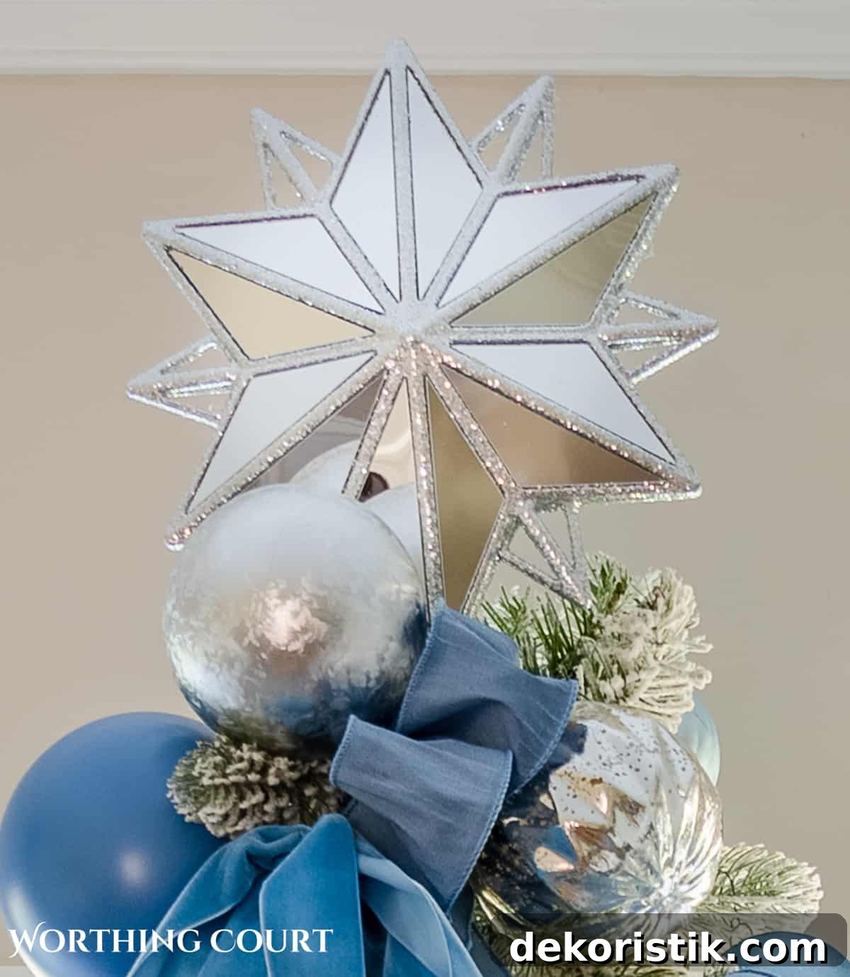 Flocked Christmas tree decorated with French blue and silver ornaments and ribbon topped with a mirrored silver star