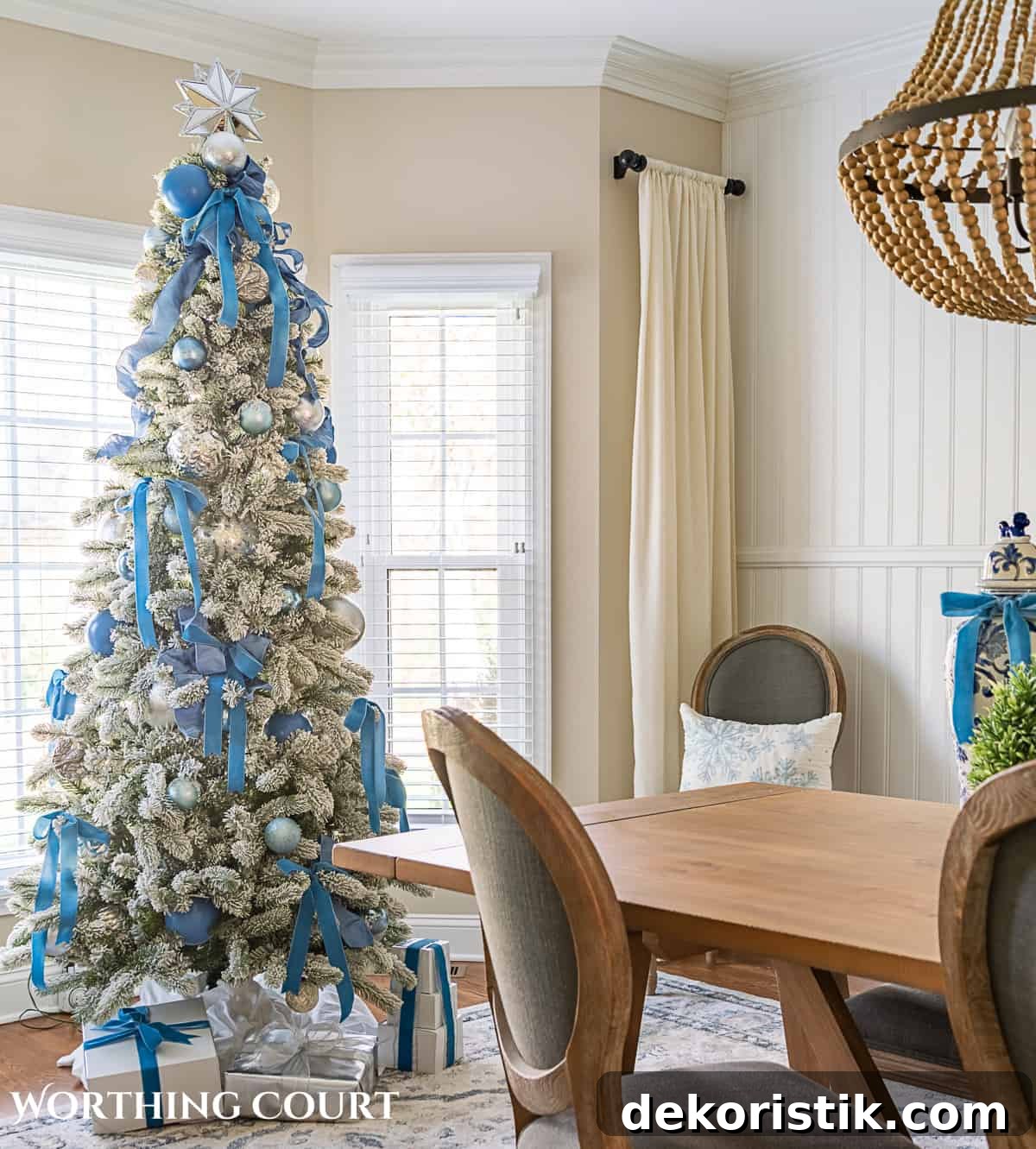 Flocked Christmas tree in a bay window decorated with French blue and silver ornaments and ribbon