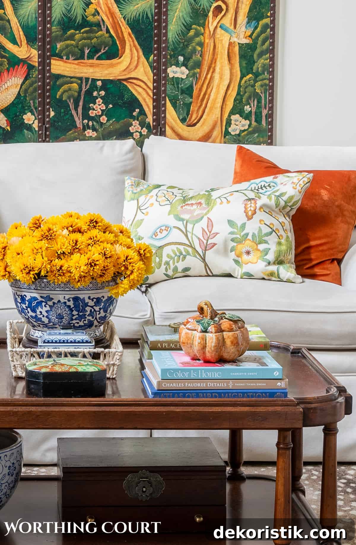 decorative wall screen hanging above a beige couch with fall throw pillows and a brown wood coffee table with fall decorations