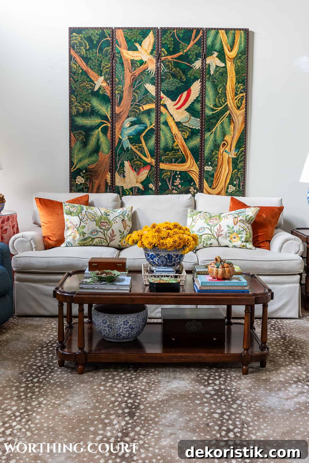 decorative wall screen hanging above a beige couch with fall throw pillows and a brown wood coffee table with fall decorations