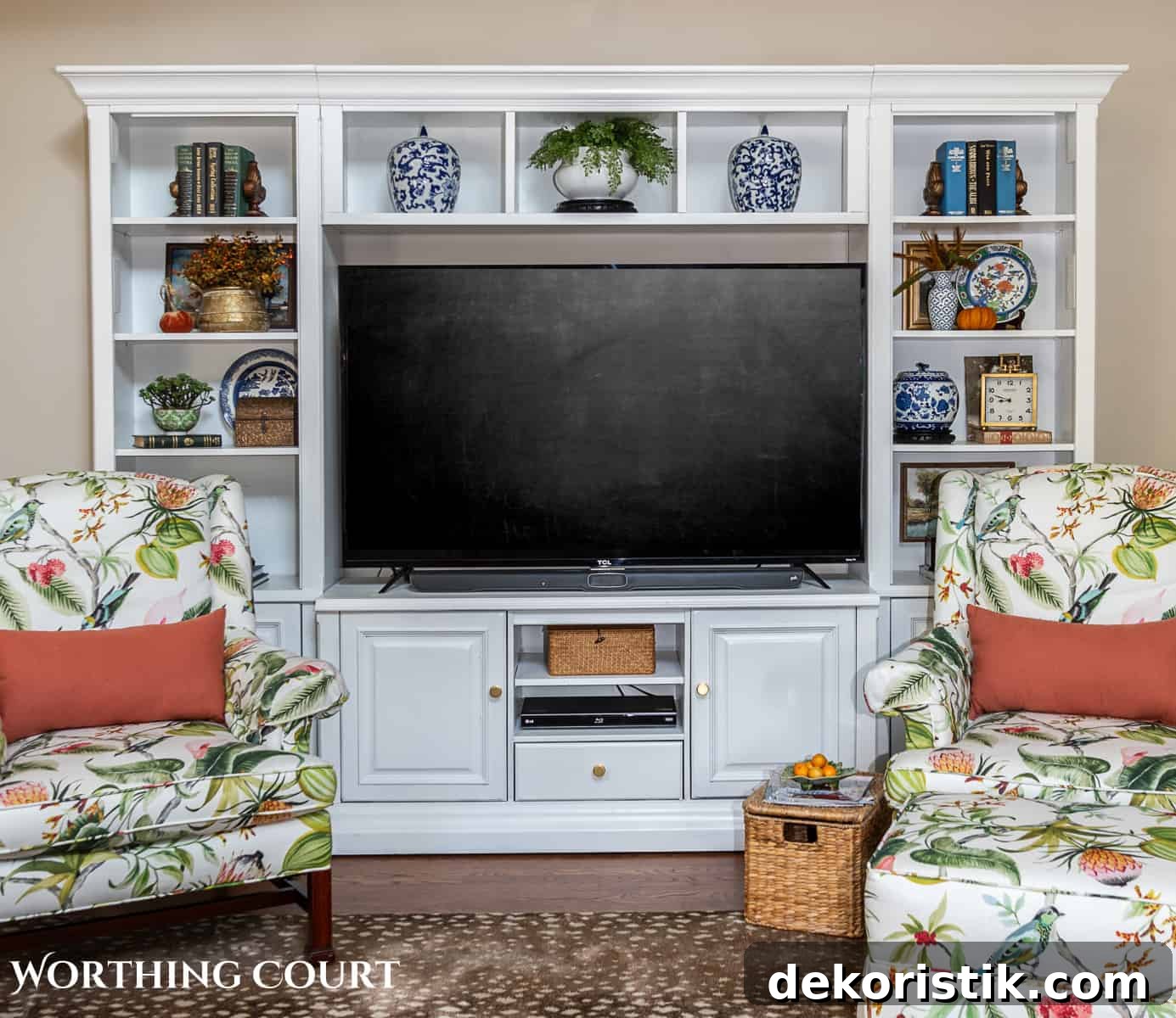 two floral upholstered arm chairs in front of a white media center with fall decorations