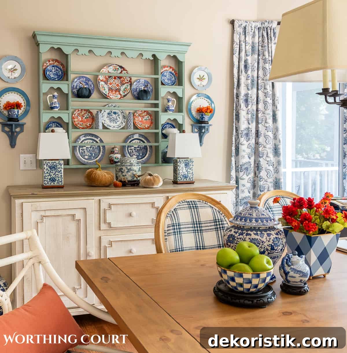 plate rack above a white sideboard filled with blue and white dishes and orange dishes for fall and a fall centerpiece on the dining table