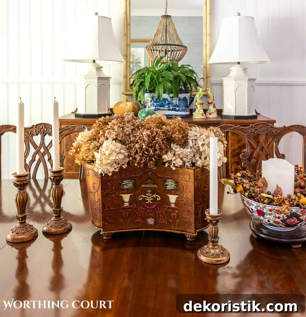fall centerpiece on a dining table with dried hydrangeas in a brown cachepot flanked by gold candlesticks