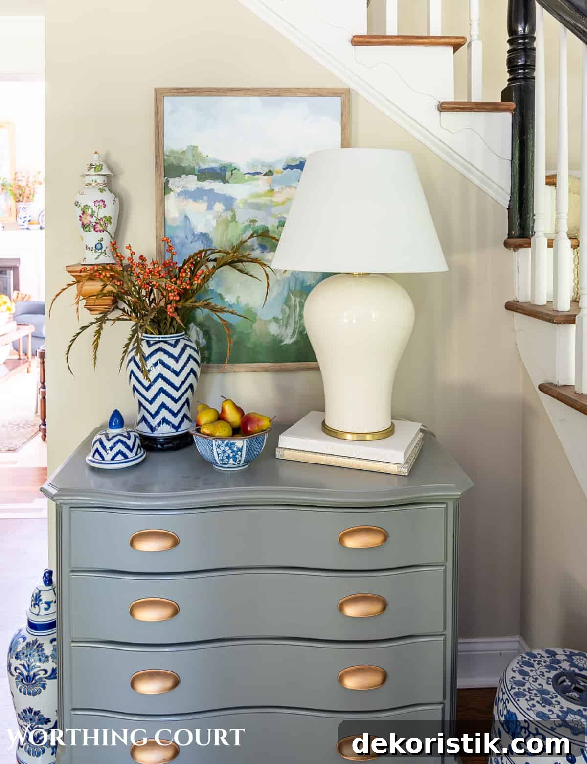gray chest topped with a blue and white vase filled with fall stems and a white ginger jar shaped lamp
