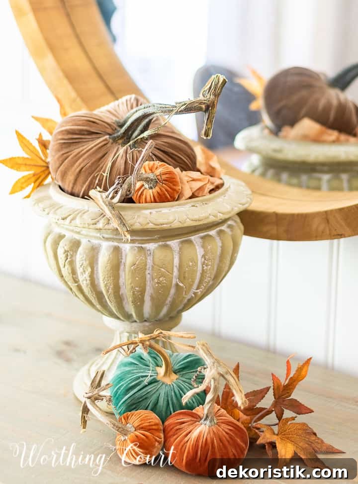 various colored velvet pumpkins and fall leaves in an urn and on the table surface