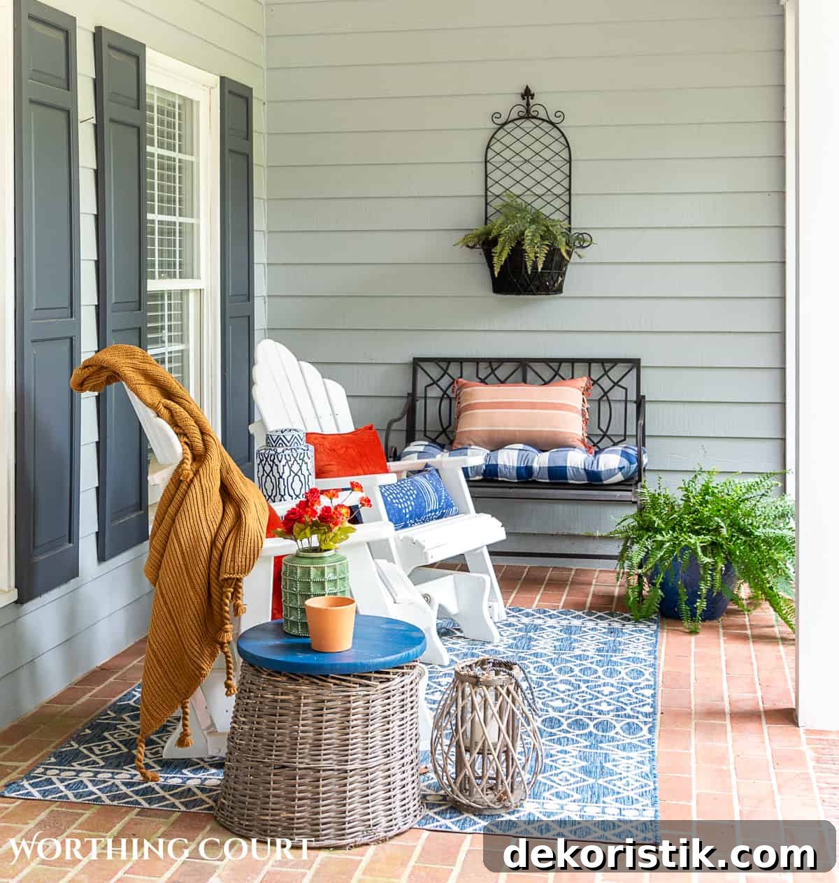 seating area on a large front porch decorated for fall with white gliders and other accessories