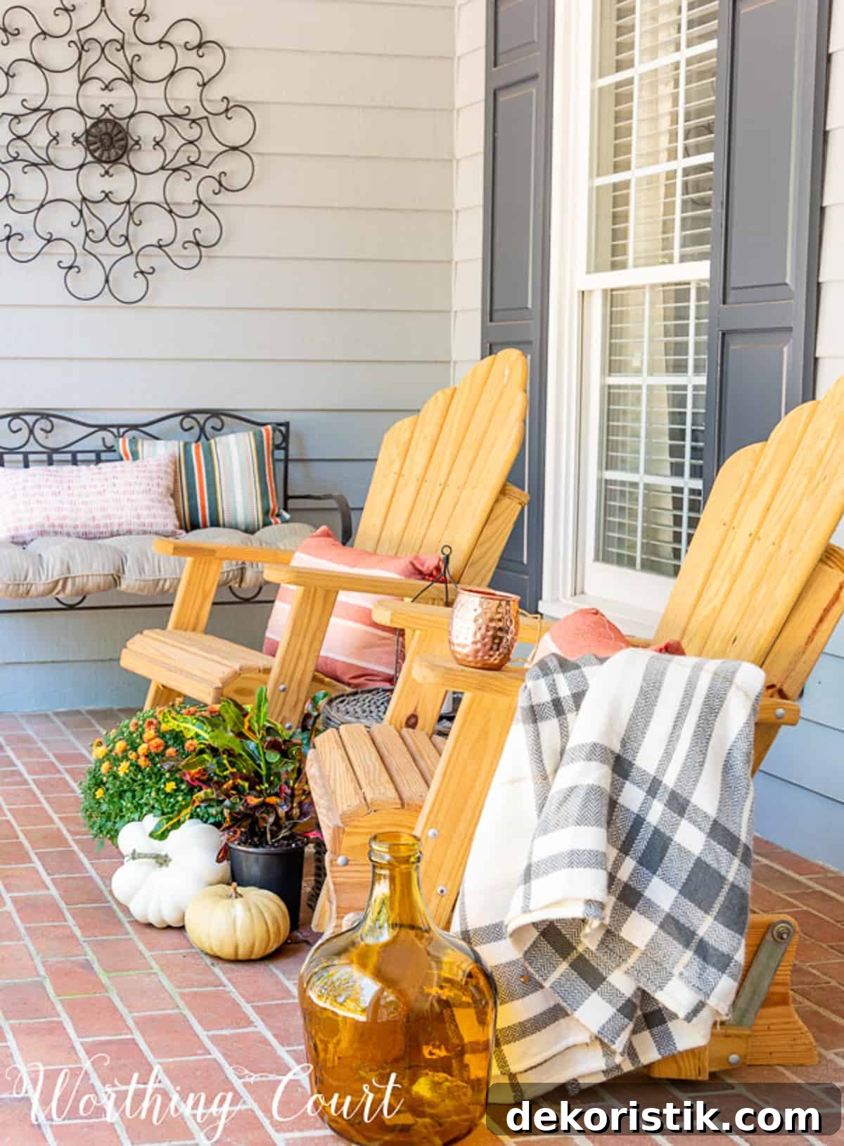 two wood gliders on front porch with fall decor