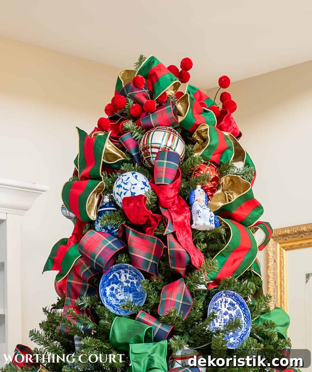 Top of Christmas tree with green and red ribbon, red ball picks and blue and white ornaments