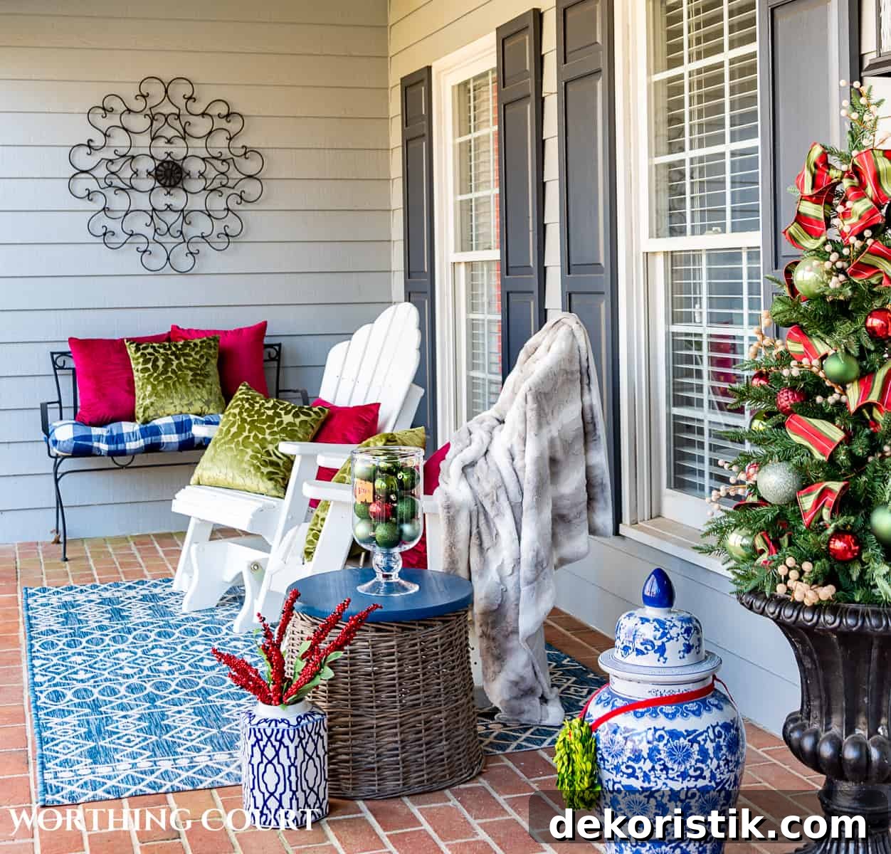 two white adirondack chairs on a front porch decorated with red and green for Christmas