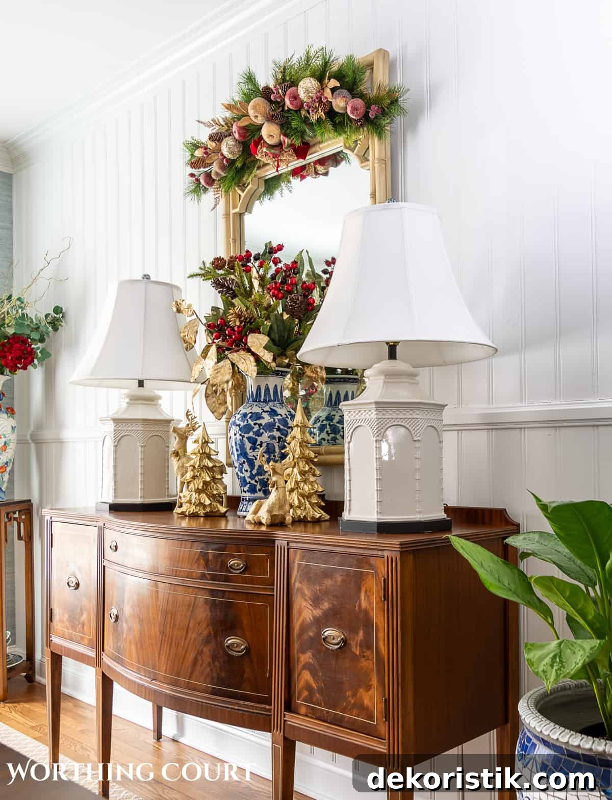 brown wood sideboard in front on white paneled wall with white lamps and Christmas decorations