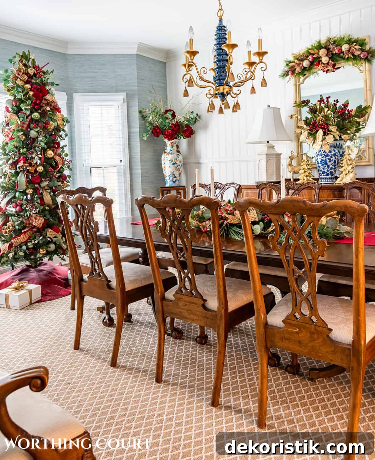 Dining room with traditional wood furniture decorated for Christmas with sage green, burgundy, and gold decorations.