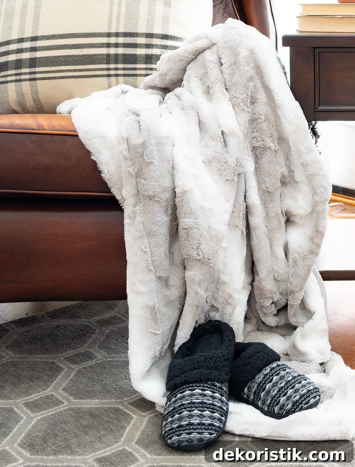 faux fur blanket thrown over the arm of a brown leather chair and a pair of slipper