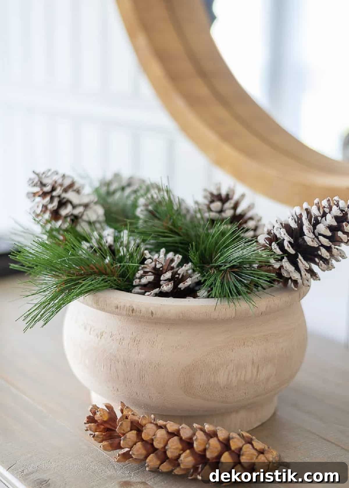 wooden bowl filled with faux evergreens and pinecones for winter decor