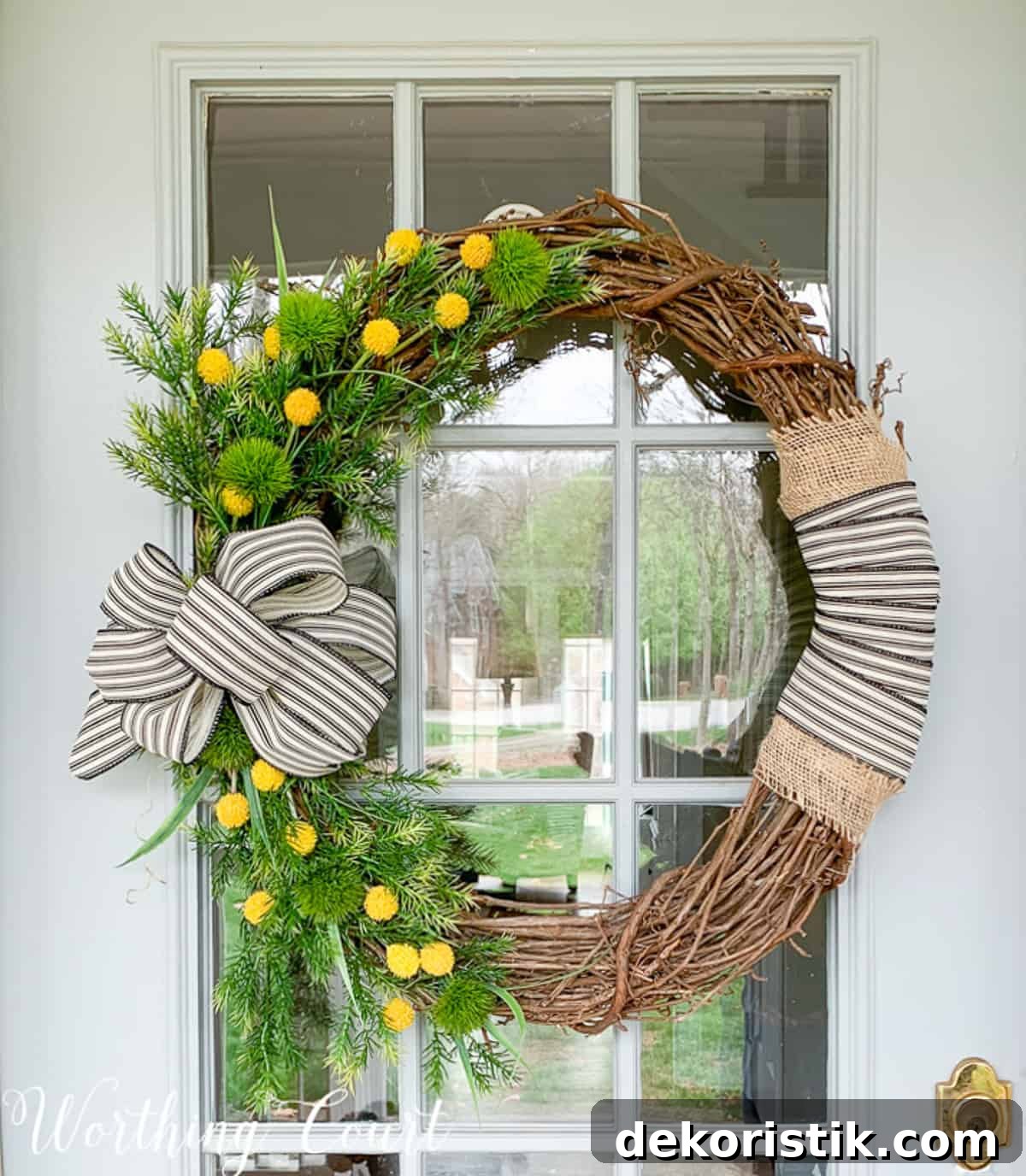 grapevine wreath decorated with yellow flowers, greenery stems, and burlap and black and white ribbon for spring