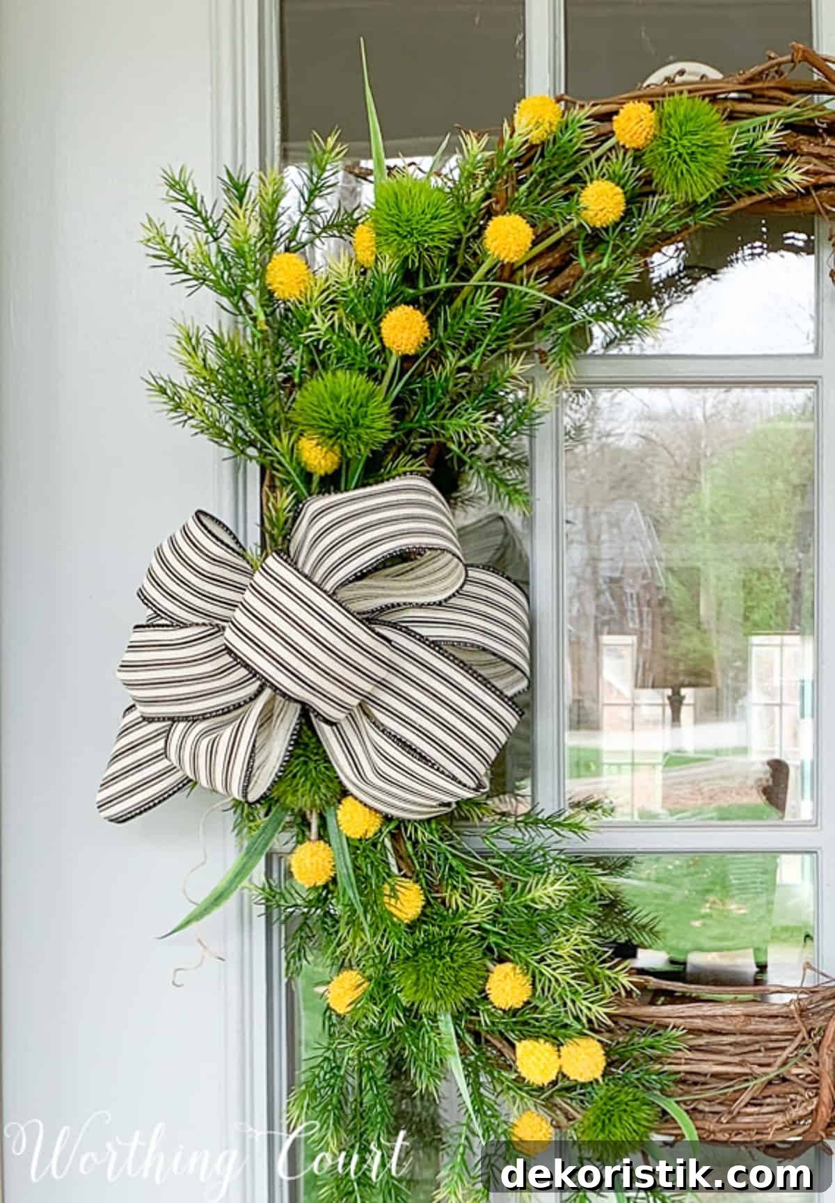 grapevine wreath decorated with yellow flowers, greenery stems, and burlap and black and white ribbon for spring