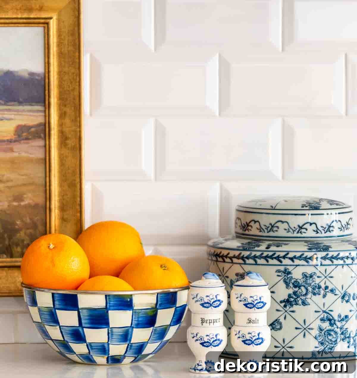 blue and white accessories and oranges in a bowl in front of a white subway tile backsplace