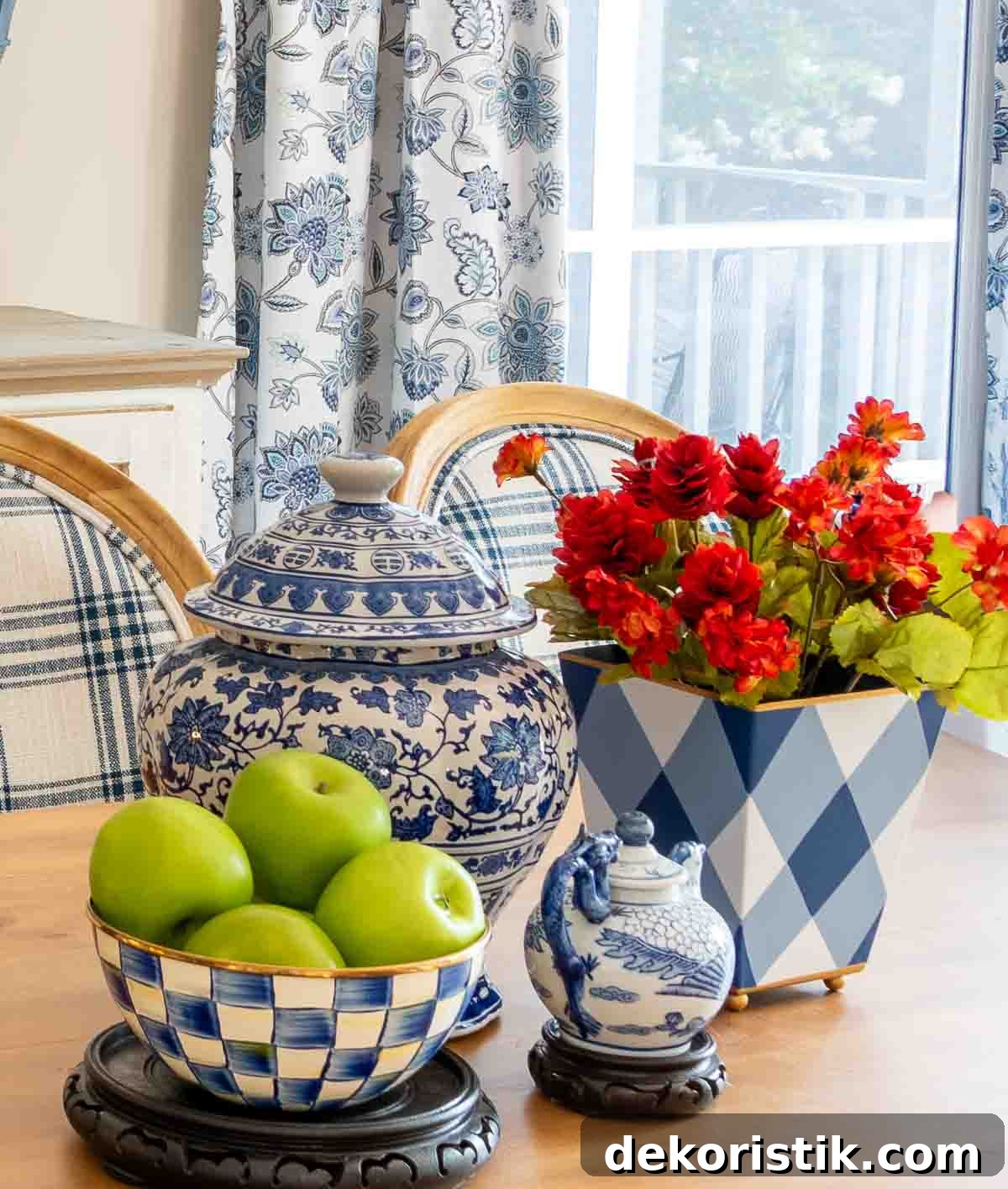August centerpiece with blue and white accessories including a blue and white checked bowl filled with green apples and a container with fall colored flowers