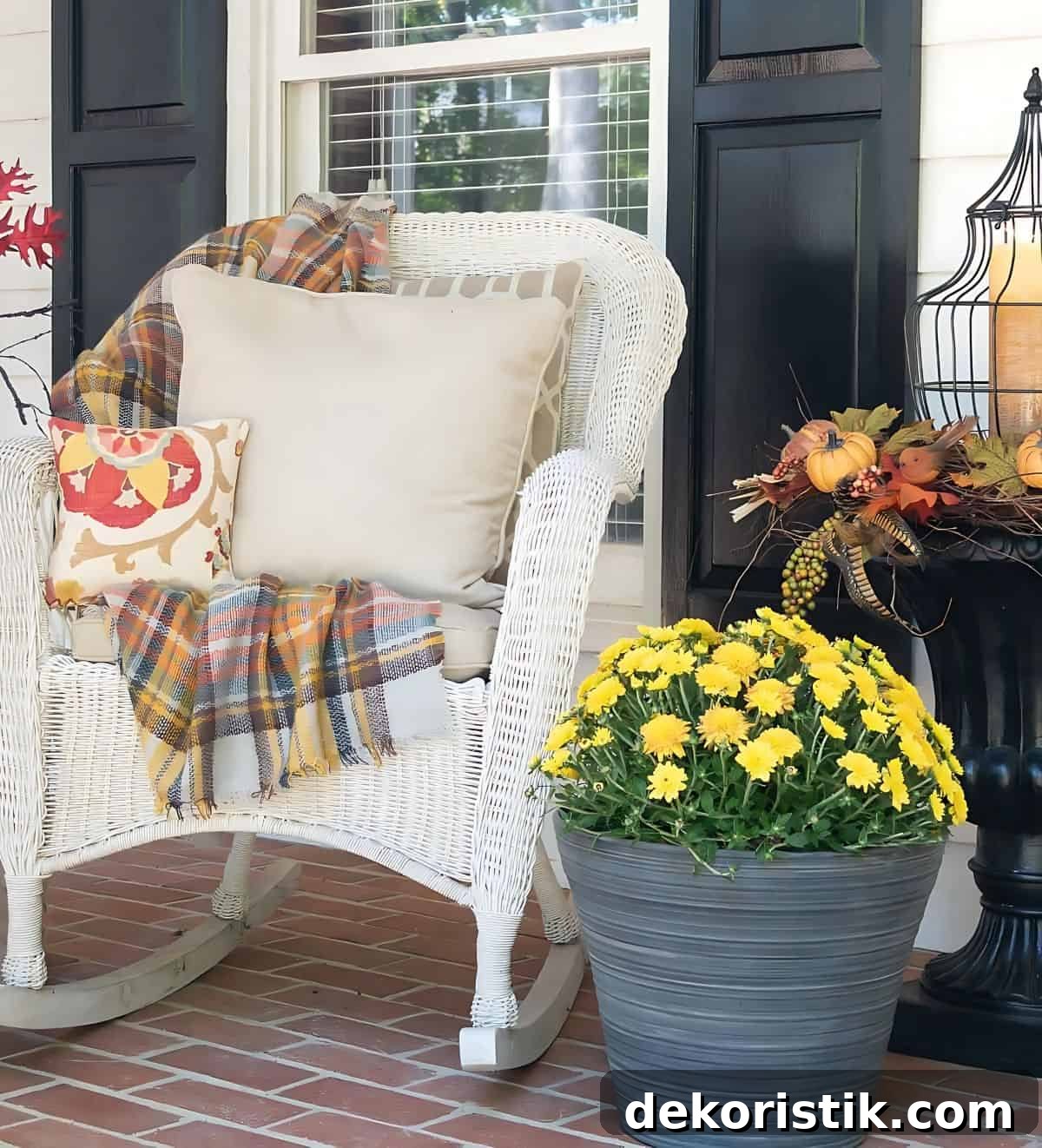 white wicker rocking chair with fall pillows and a plaid fall throw blanket