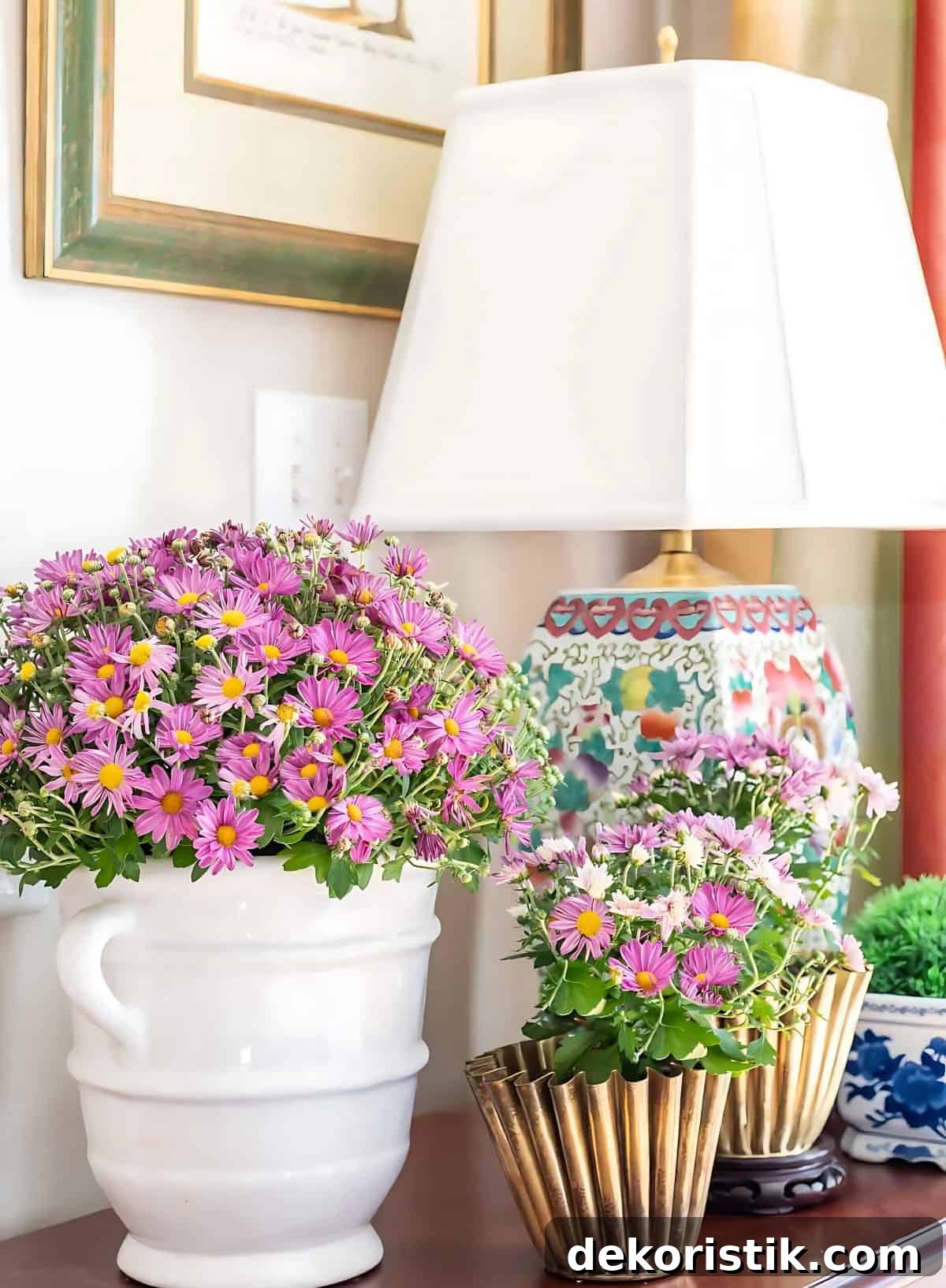 three purple mums in various containers on a wooden chest