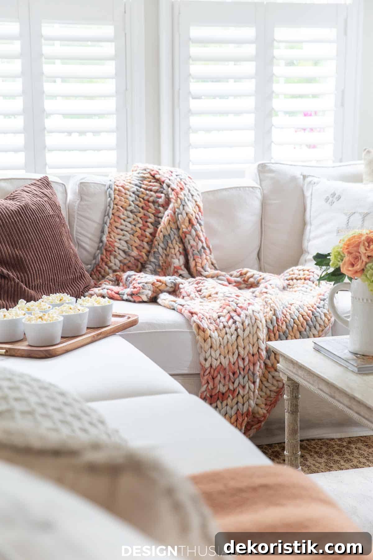 a white sectional sofa in front of window with plantation shutters