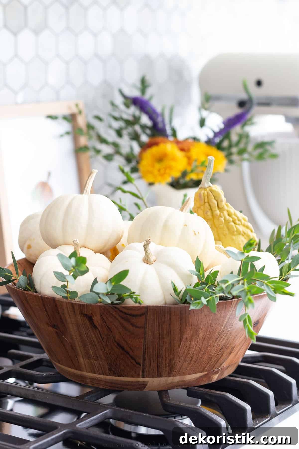 round wooden bowl filled with white mini pumpkins and greenery