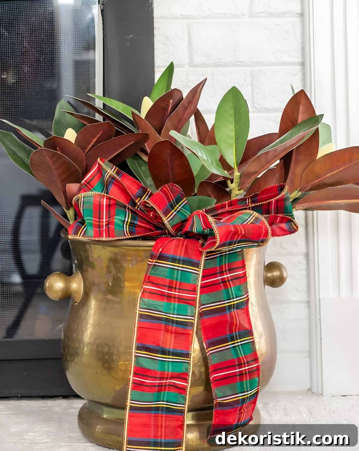 magnolia stems and Christmas ribbon in a brass container