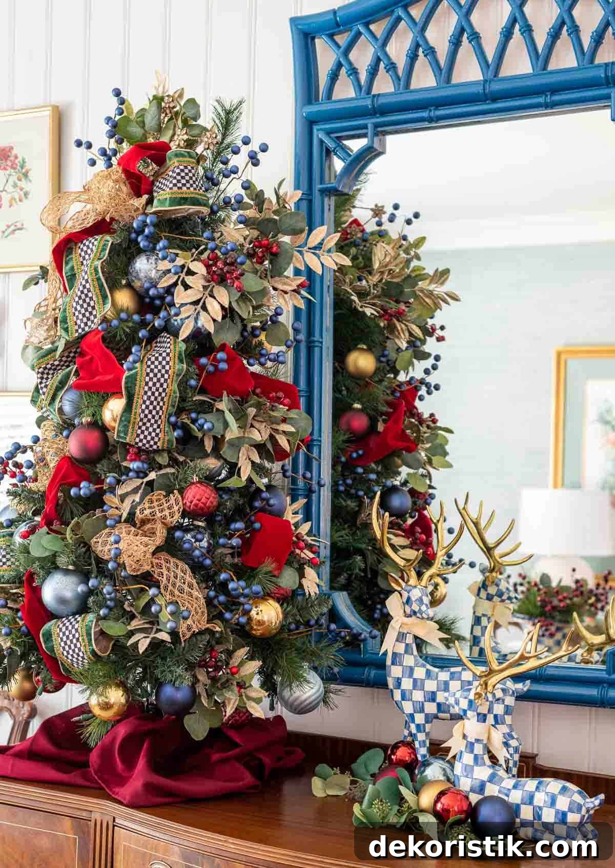 Decorated Christmas tree with blue, red, gold ornaments and ribbons in a holiday home setting.