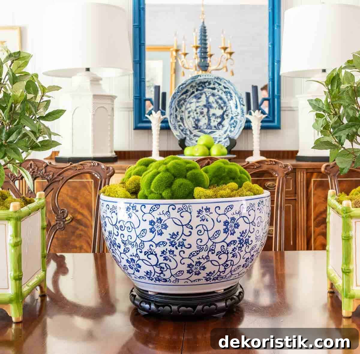 large blue and white bowl filled with moss and moss balls in a dining room table centerpiece