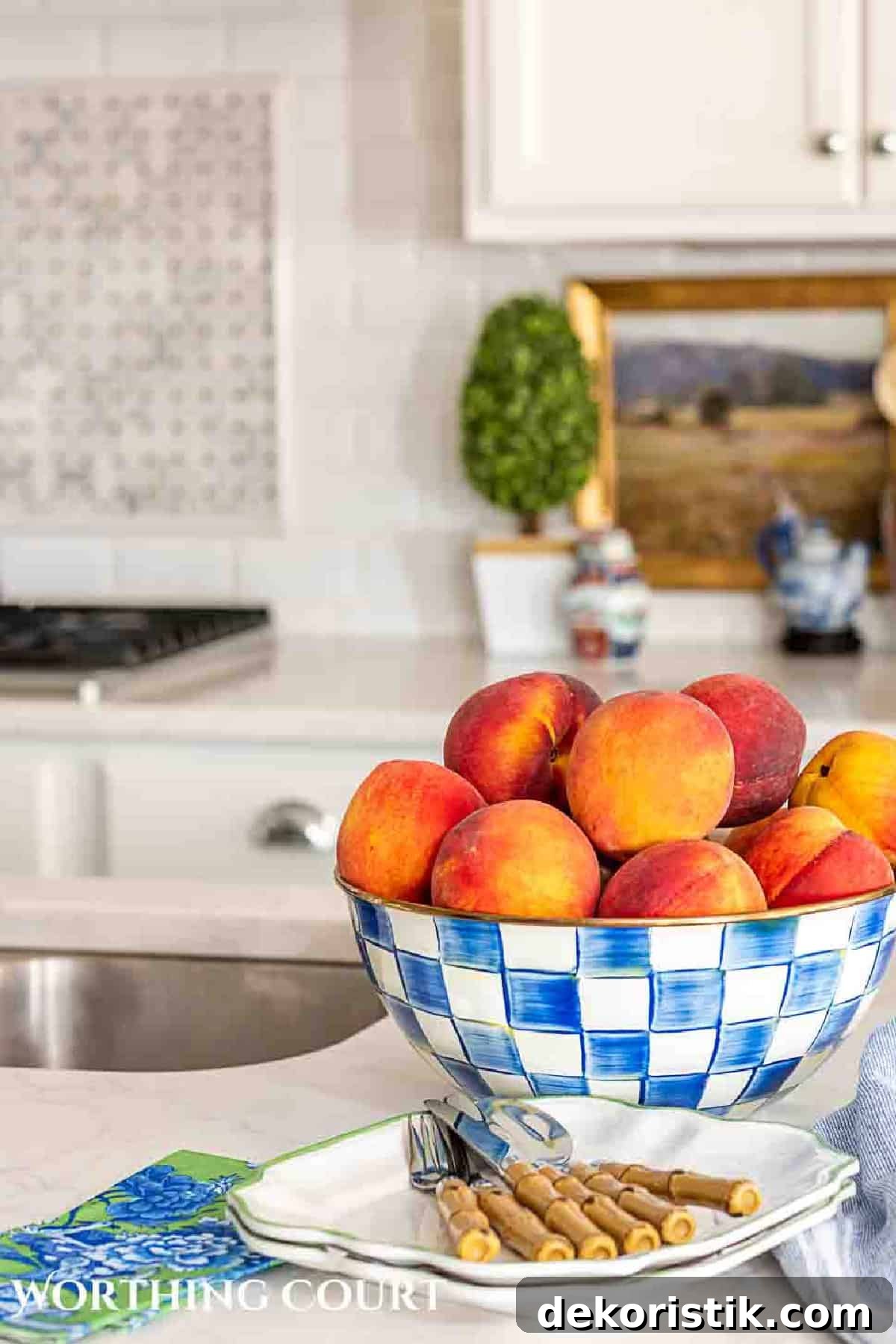 bowl of peaches in a blue and white checked bowl on a white kitchen counter
