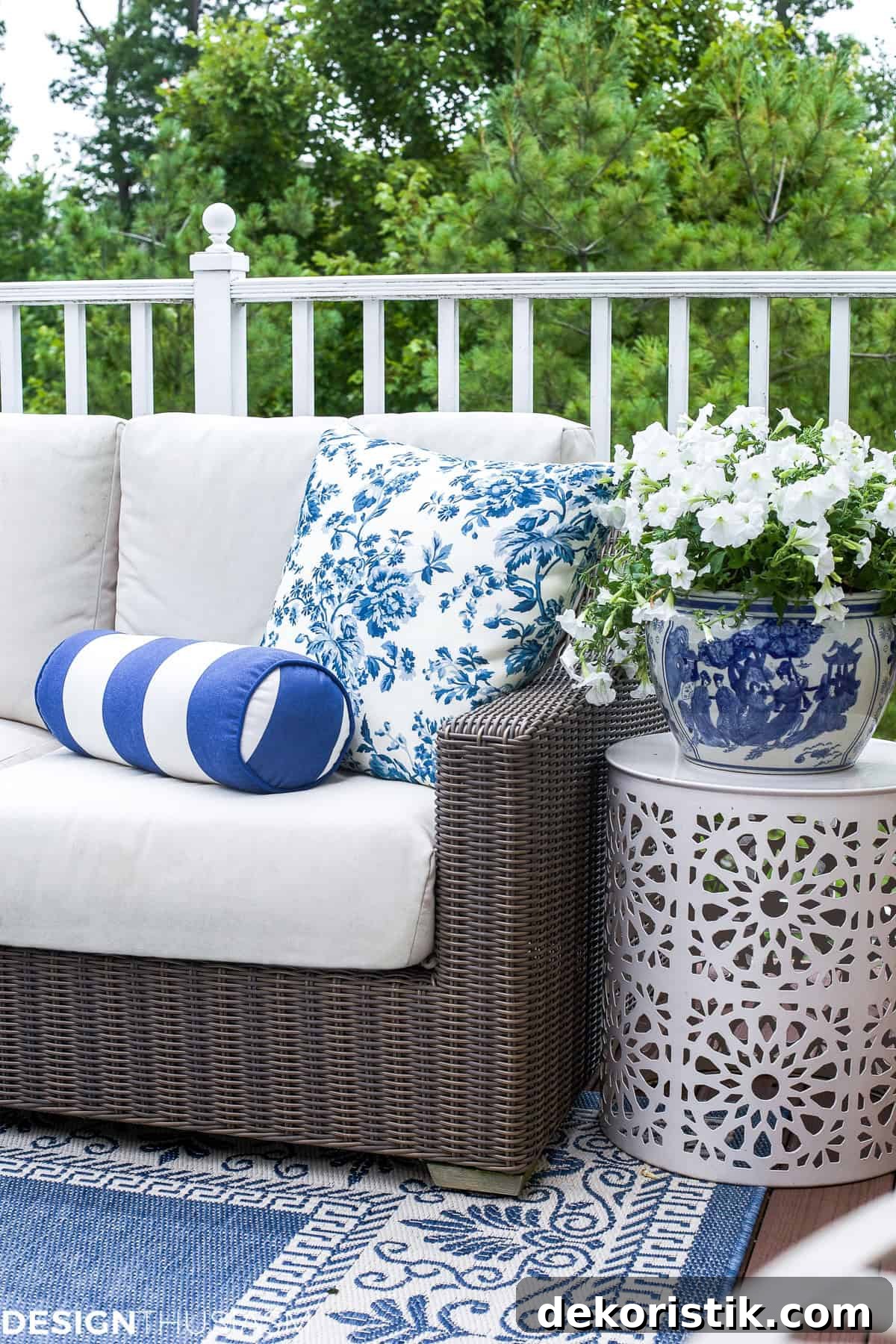 One end of a neutral outdoor sofa with pillows and a side table on a deck