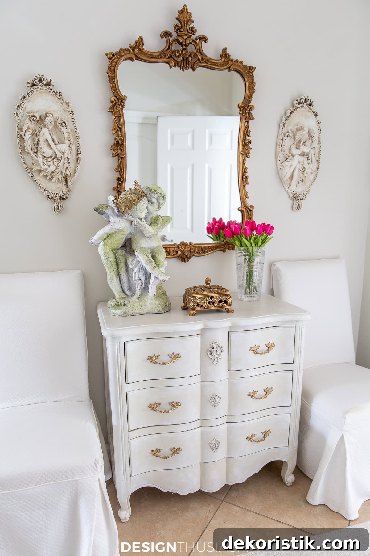 white French provencal chest between two white slip covered parsons chairs topped with french style decor