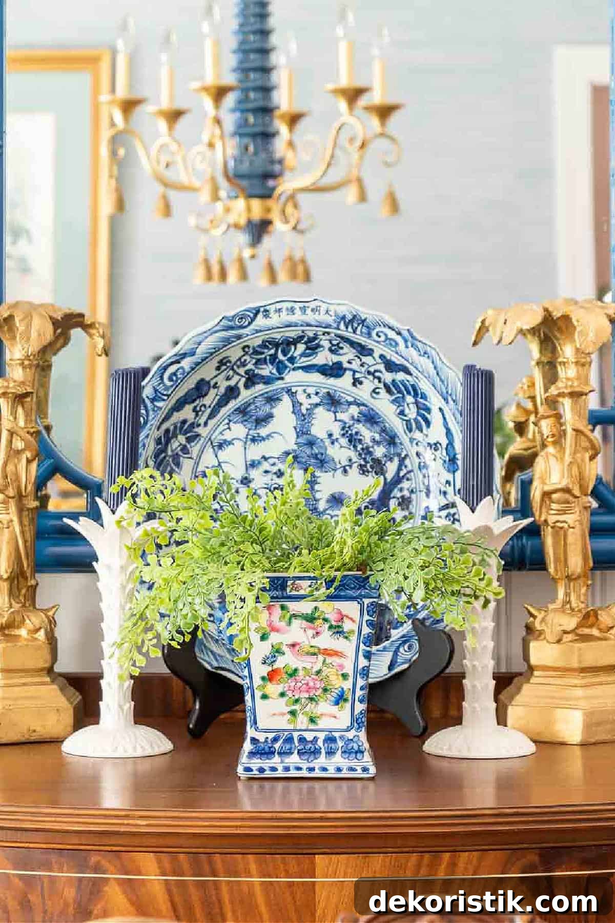 Blue and white chinoiserie decor arranged on a buffet in front of a mirror