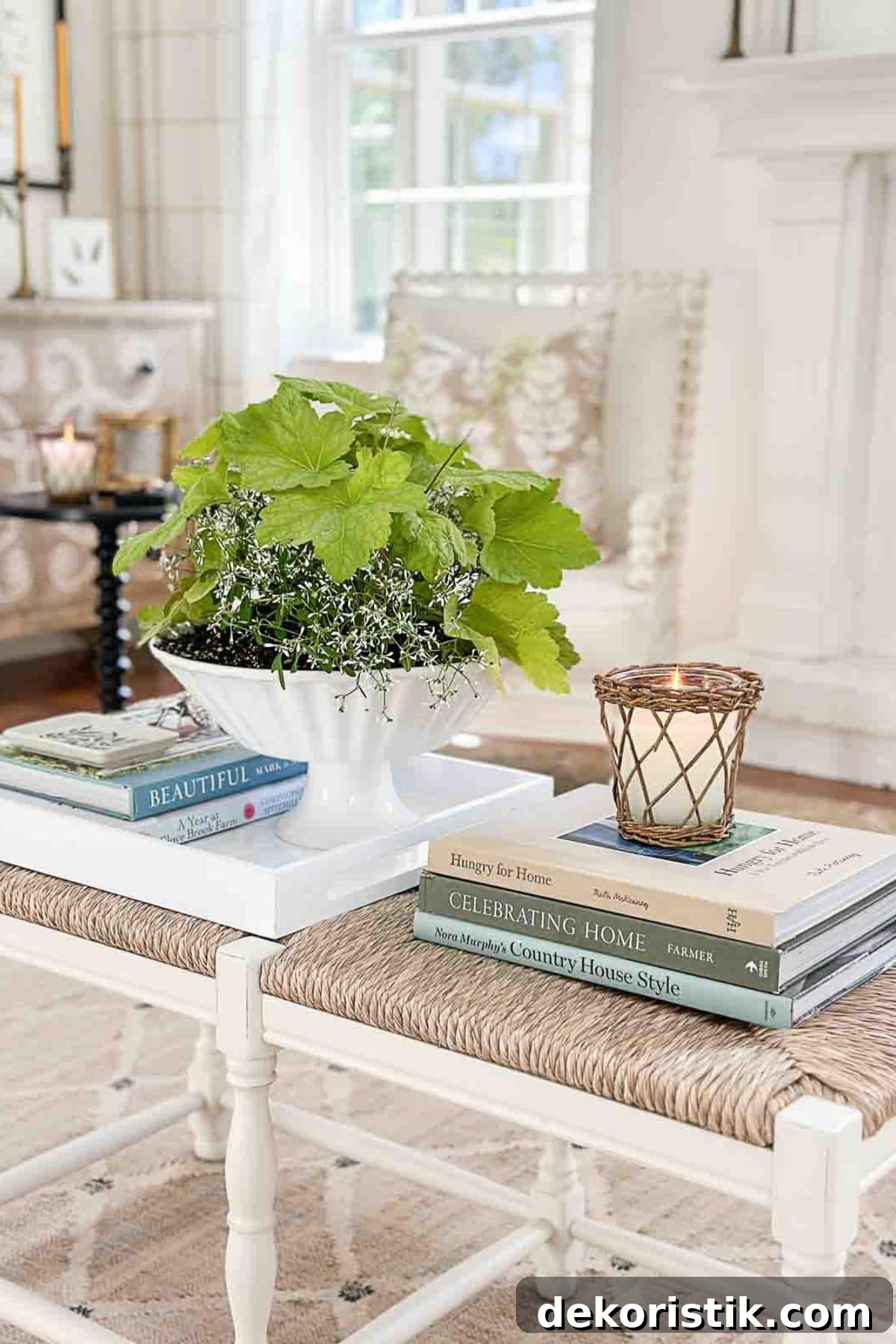 summer vignette with a white pedestal bowl filled with greenery on a coffee table