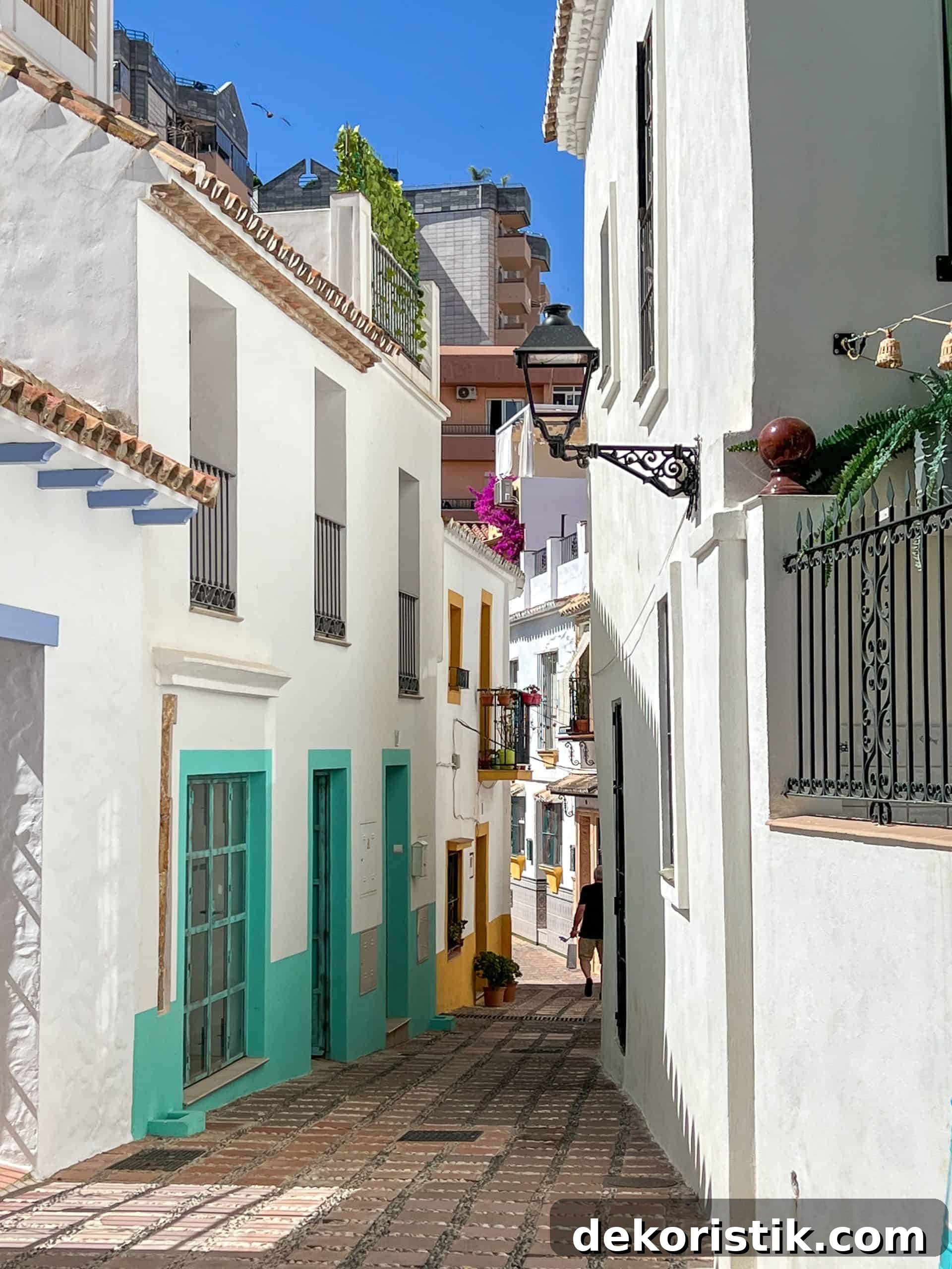 narrow alleyway between white stucco walls with turquoise doors