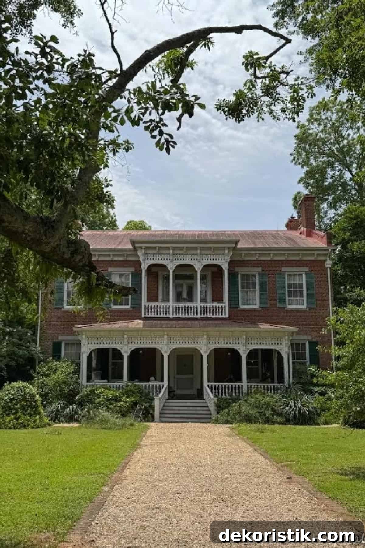front of historic red brick home with white victorian style trim work and green shutters
