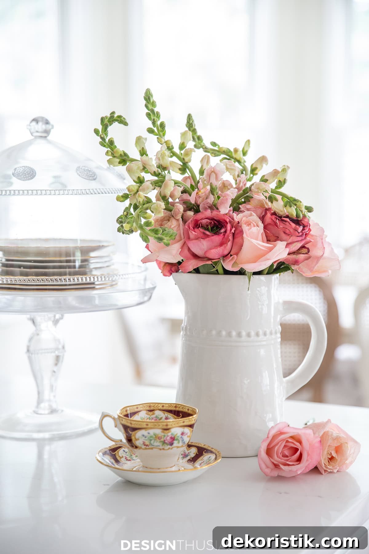 White vase with pink summer flowers in a simple tabletop vignette