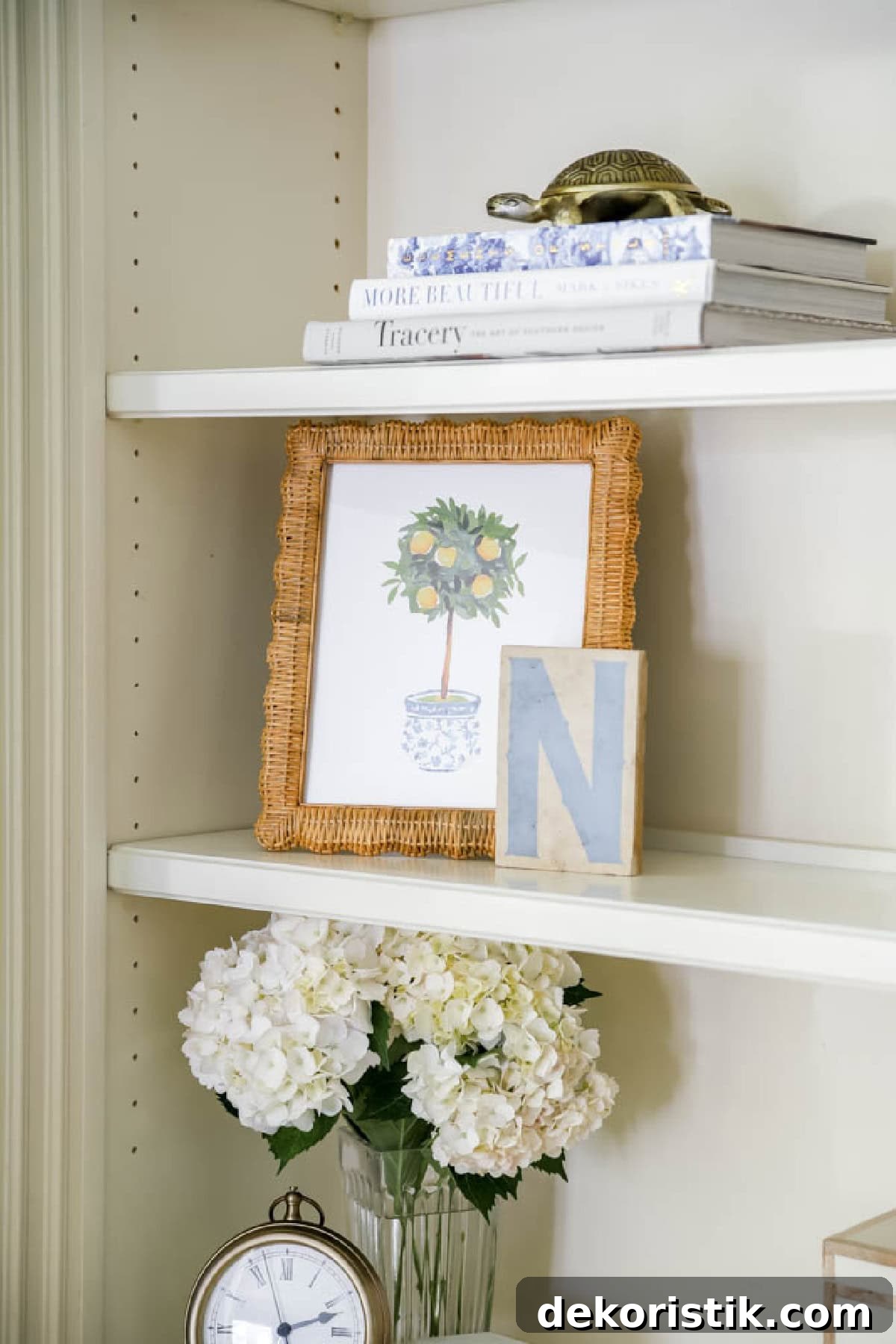 lemon tree topiary print in a rattan frame on a bookcase with other decor
