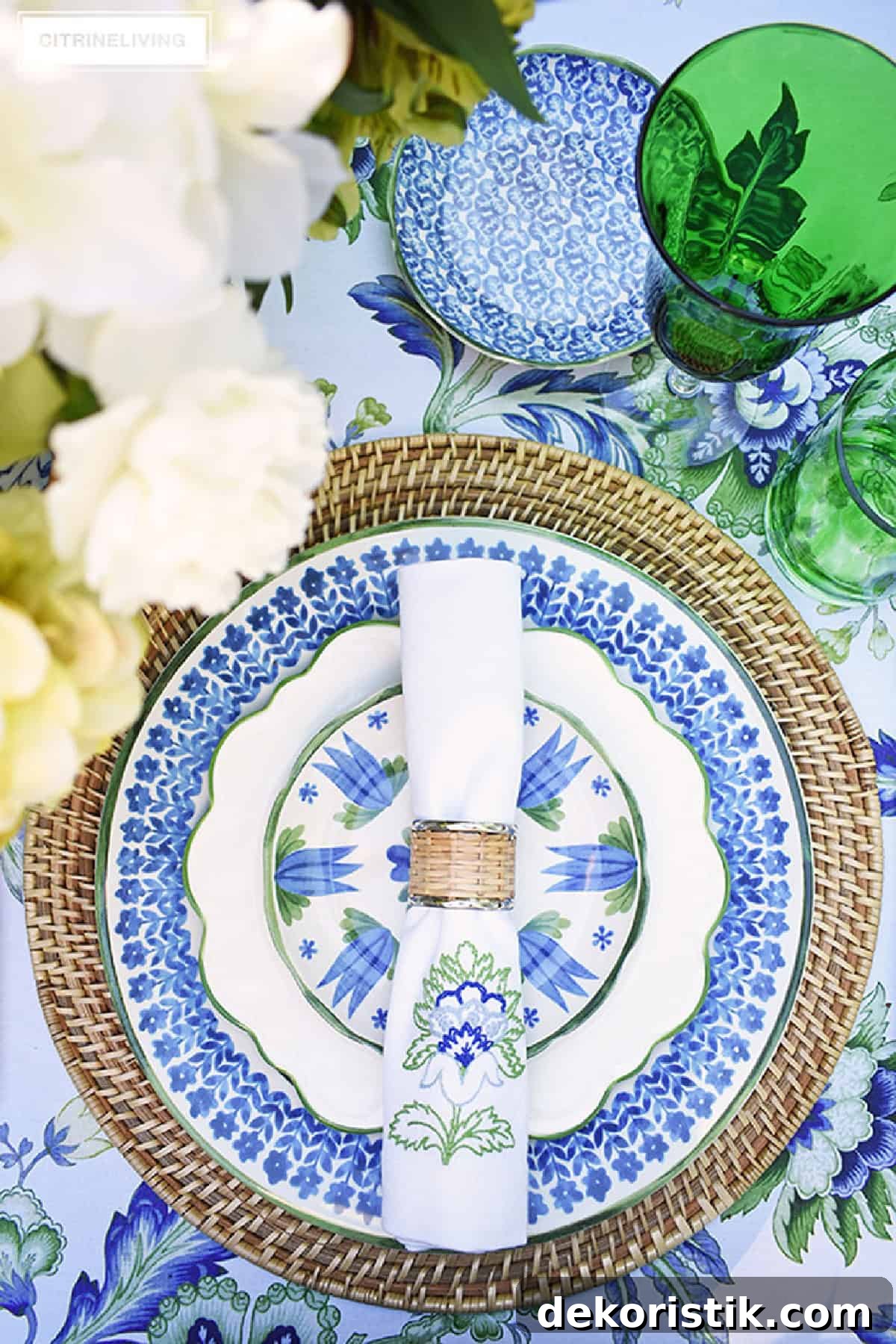 place setting with ratan charger topped with blue, white and green plates and napkin