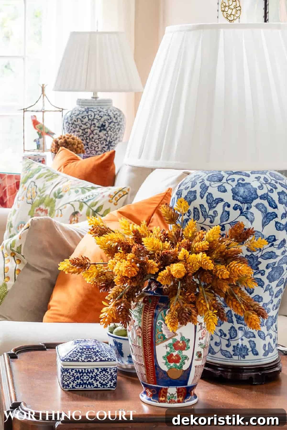 faux fall florals in a chinoiserie vase beside a blue and white lamp