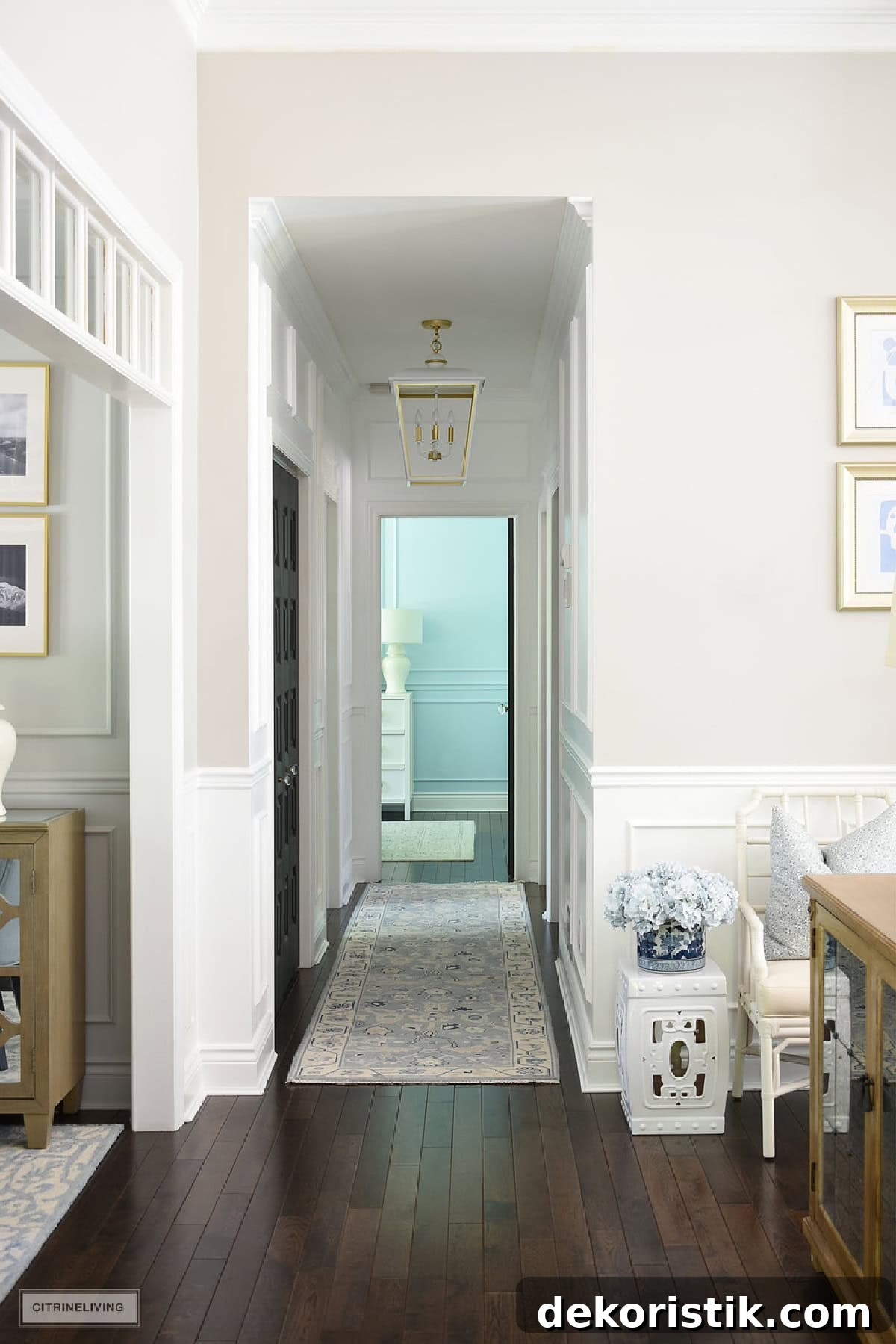 view down a hallway with white walls, millwork, dark wood floors, and a traditional style blue rug runner