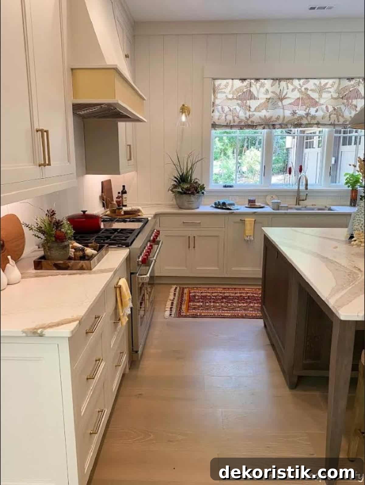 view into a kitchen between an island and counter with a gas range and large window above the sink