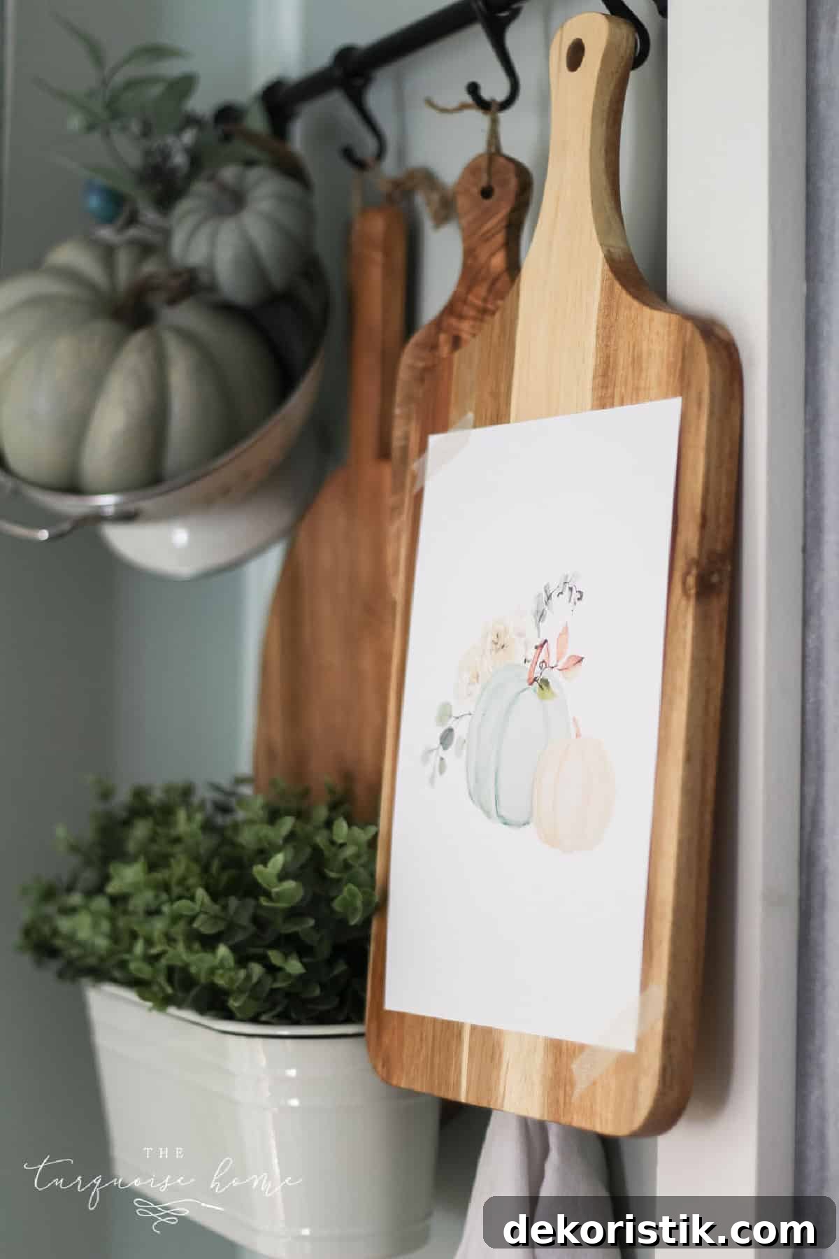 Pumpkin-themed wall art and wooden cutting boards on hook rack in farmhouse kitchen decor.