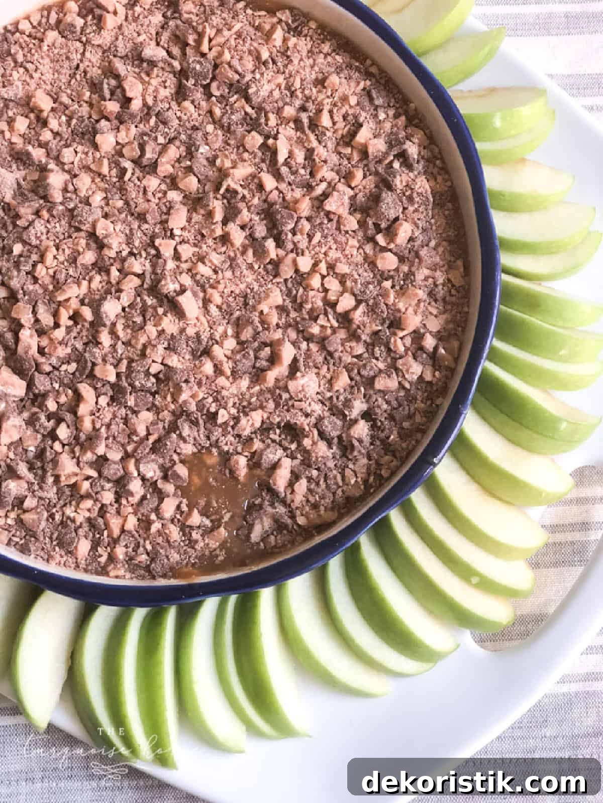 Crumbled chocolate cake with sliced green apples decoratively arranged on a white plate.