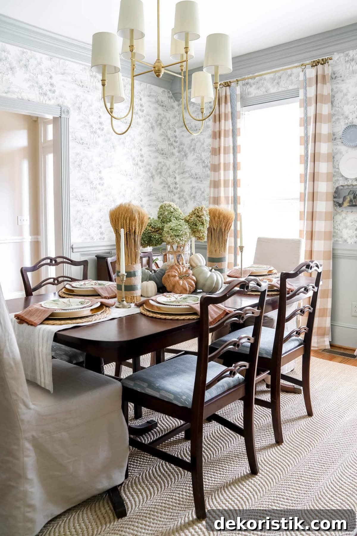 Vintage wooden dining table with fall-inspired decor including pumpkins and dried flowers.