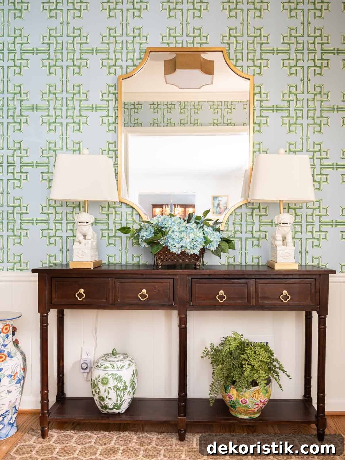 views of a small foyer decorated with chinoiserie accessories, a wood console table, and with blue and green lattice patterned wallpaper