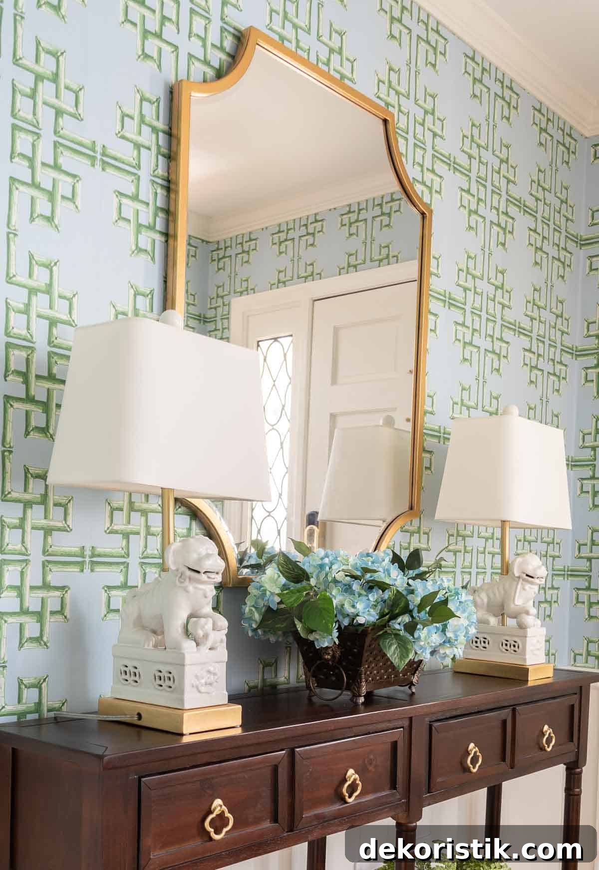 views of a small foyer decorated with chinoiserie accessories, a wood console table, and with blue and green lattice patterned wallpaper