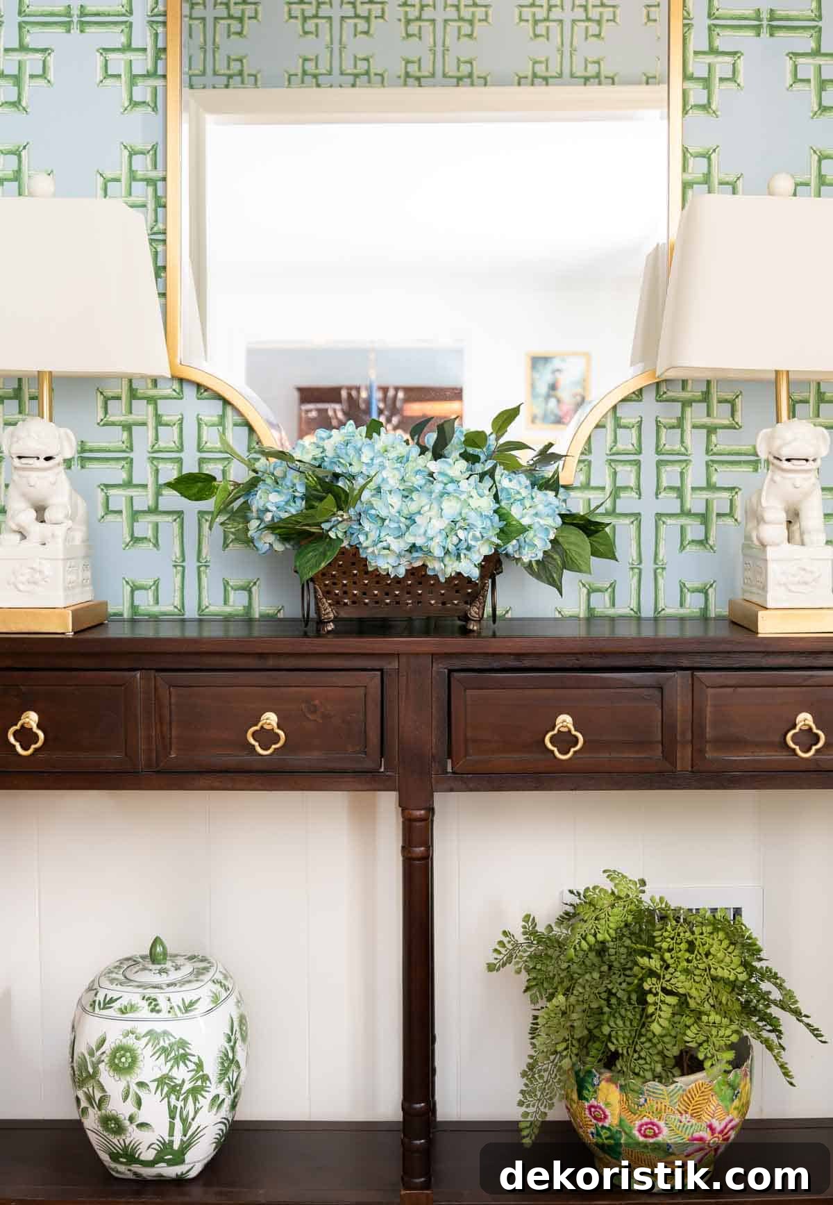 views of a small foyer decorated with chinoiserie accessories, a wood console table, and with blue and green lattice patterned wallpaper
