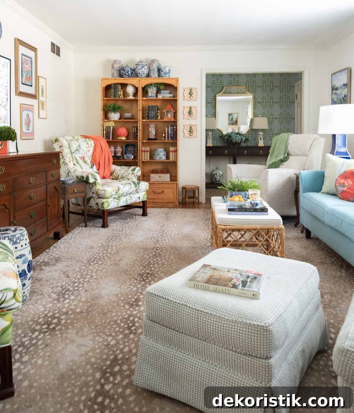Small Living Room Ideas: How We Made Ours Stylish and Functional 8 partial view of a living room decorated with colorful patterns, chinoiserie accents, and traditional style furniture. Includes a blue velvet loveseat, faux bamboo bookcase, antelope print area rug, samsung frame tv in a gallery wall with art prints, framed needlepoint and plates, with coral accents